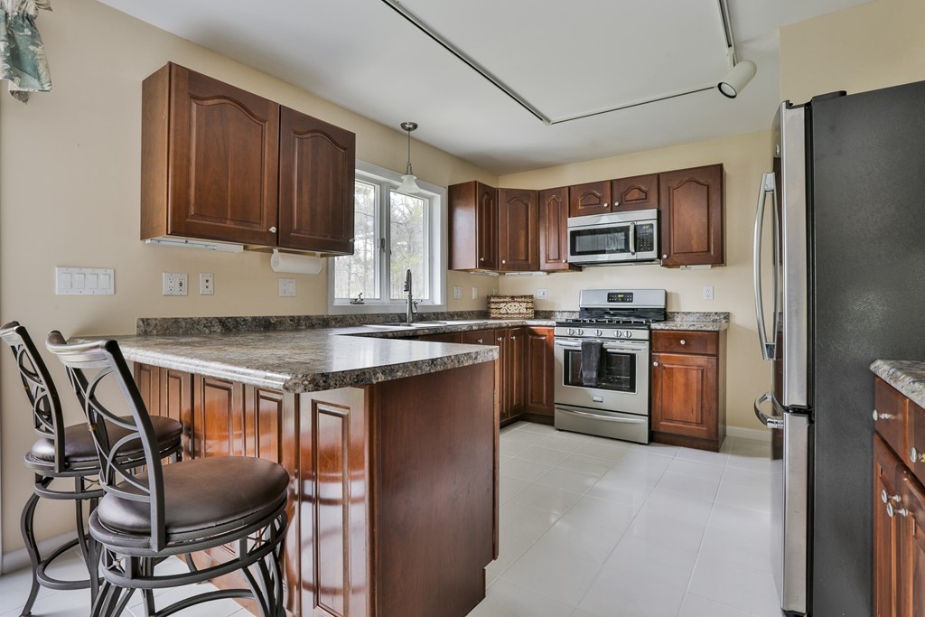 93 Beach Road Salisbury, MA 01952 - Photo 14 of 30 a kitchen with stainless steel appliances granite countertop a stove top oven a sink a dining table and chairs