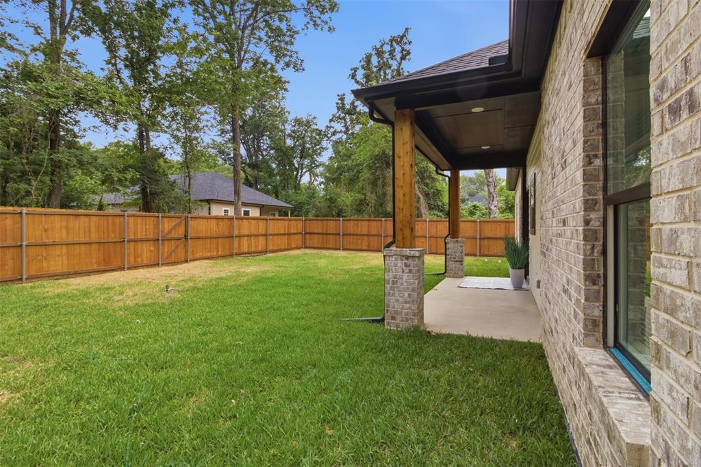 429 Waterboard Road Trinidad, TX 75163 - Photo 21 of 25 Expansive green lawn with a newly installed wood privacy fence, featuring a covered patio with brick columns, wood posts, and recessed lighting