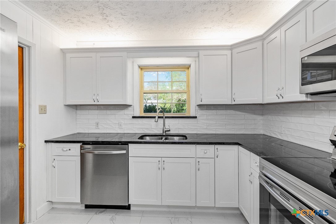 608 Berwick Road Victoria, TX 77904 - Photo 6 of 31 a kitchen with white cabinets appliances a sink and a window