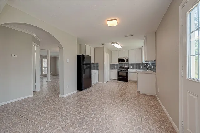 a kitchen with granite countertop white cabinets and black appliances