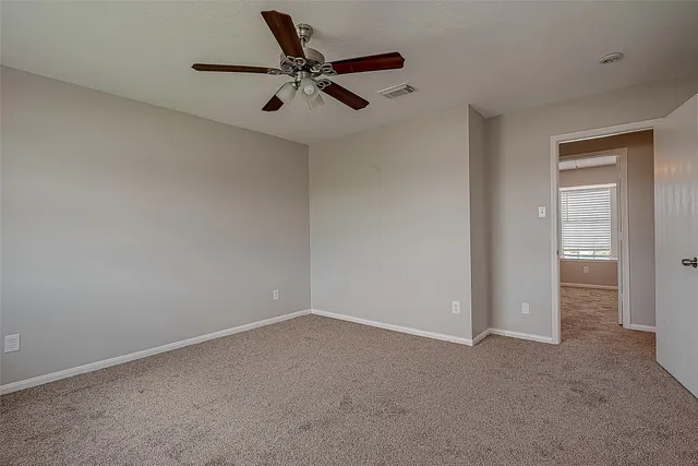 an empty room with windows and ceiling fan