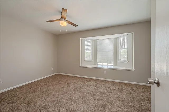 an empty room with windows and fan