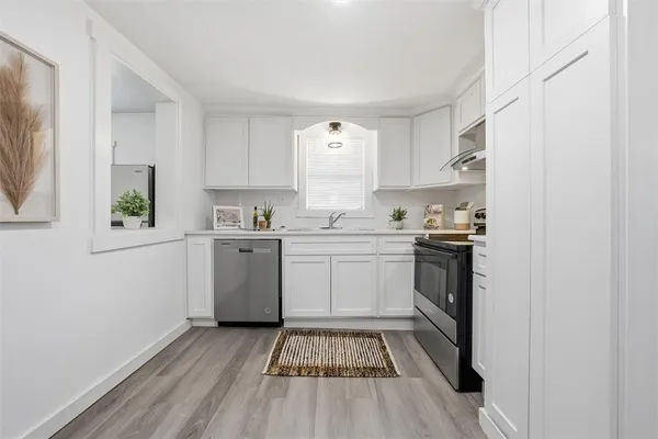 a kitchen with a sink cabinets stainless steel appliances and a window