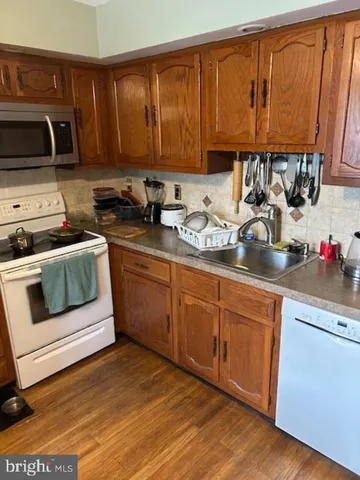 a kitchen with stainless steel appliances granite countertop a stove a sink dishwasher and cabinets with wooden floor