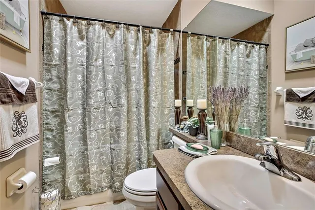 a bathroom with a granite countertop sink a toilet and shower curtain