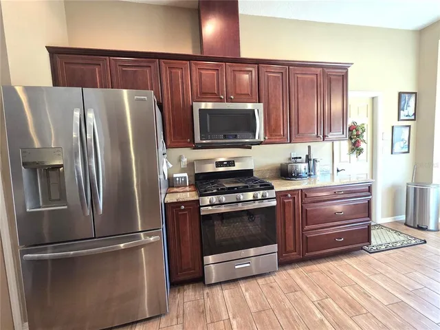 a kitchen with granite countertop a refrigerator stove and microwave