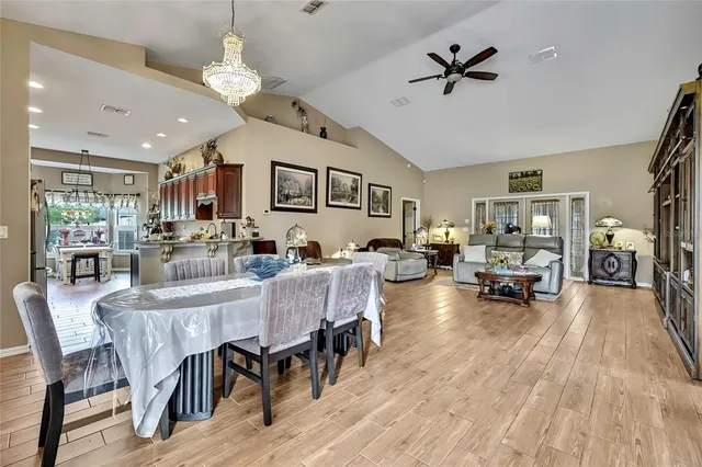 a view of dining room and livingroom with furniture wooden floor a rug a flat screen tv a rug and a chandelier