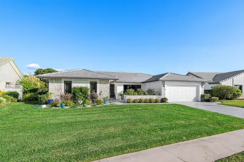 a front view of a house with a garden and trees