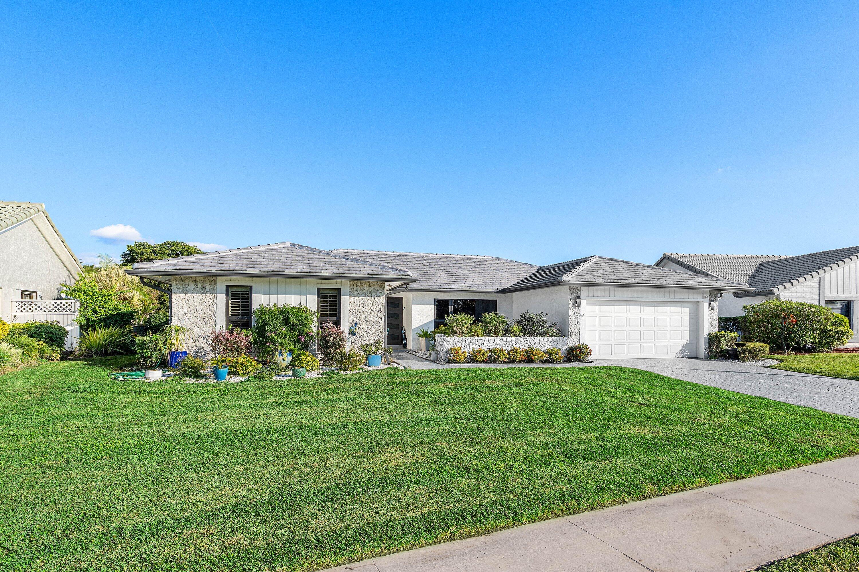 10174 Crosswind Road Boca Raton, FL 33498 - Photo 2 of 45 a front view of a house with a garden and trees