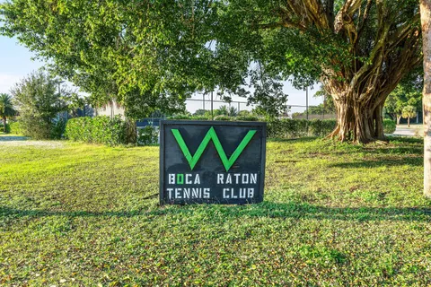 a view of a park that has a sign board large trees