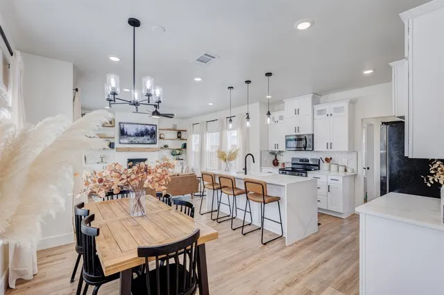 a kitchen with stainless steel appliances kitchen island granite countertop a table chairs and a refrigerator