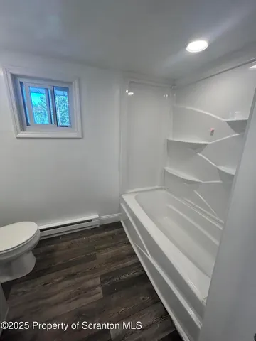 a bathroom with a toilet and a wooden floor