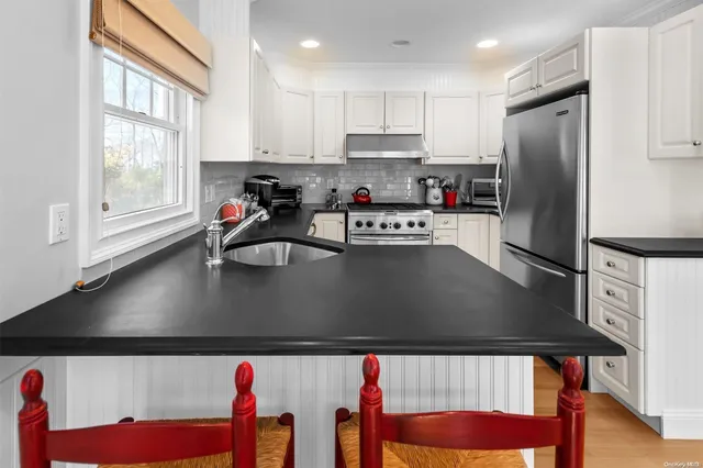 a kitchen with stainless steel appliances granite countertop a refrigerator a sink dishwasher a stove and a refrigerator with wooden floor