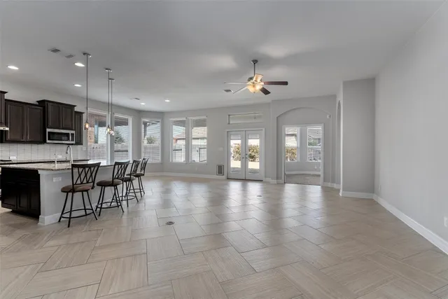 an empty room with a chandelier fan and windows