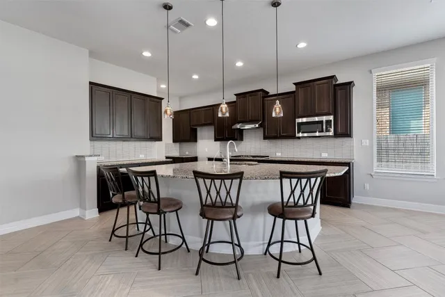 a kitchen with stainless steel appliances granite countertop wooden cabinets a stove top oven a sink and dishwasher