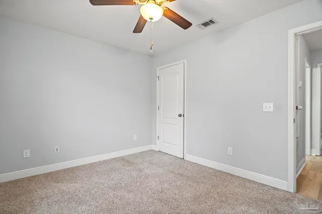 a view of a hallway with wooden floor and a bathroom