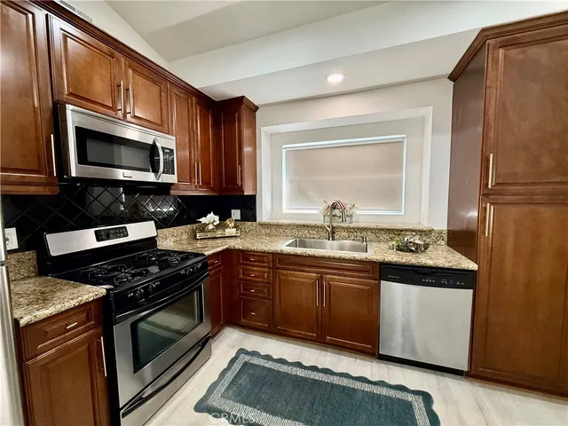 a kitchen with stainless steel appliances granite countertop a stove microwave and sink