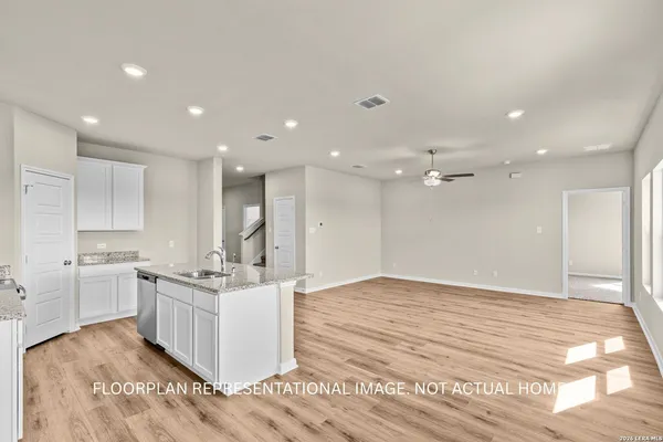a large white kitchen with kitchen island a sink stainless steel appliances and cabinets