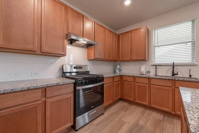 a kitchen with granite countertop wooden cabinets and a stove top oven