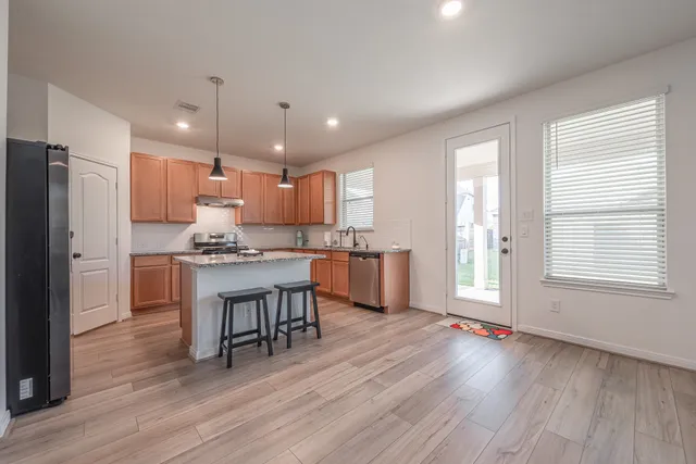 a kitchen with kitchen island granite countertop wooden floors refrigerator and cabinets