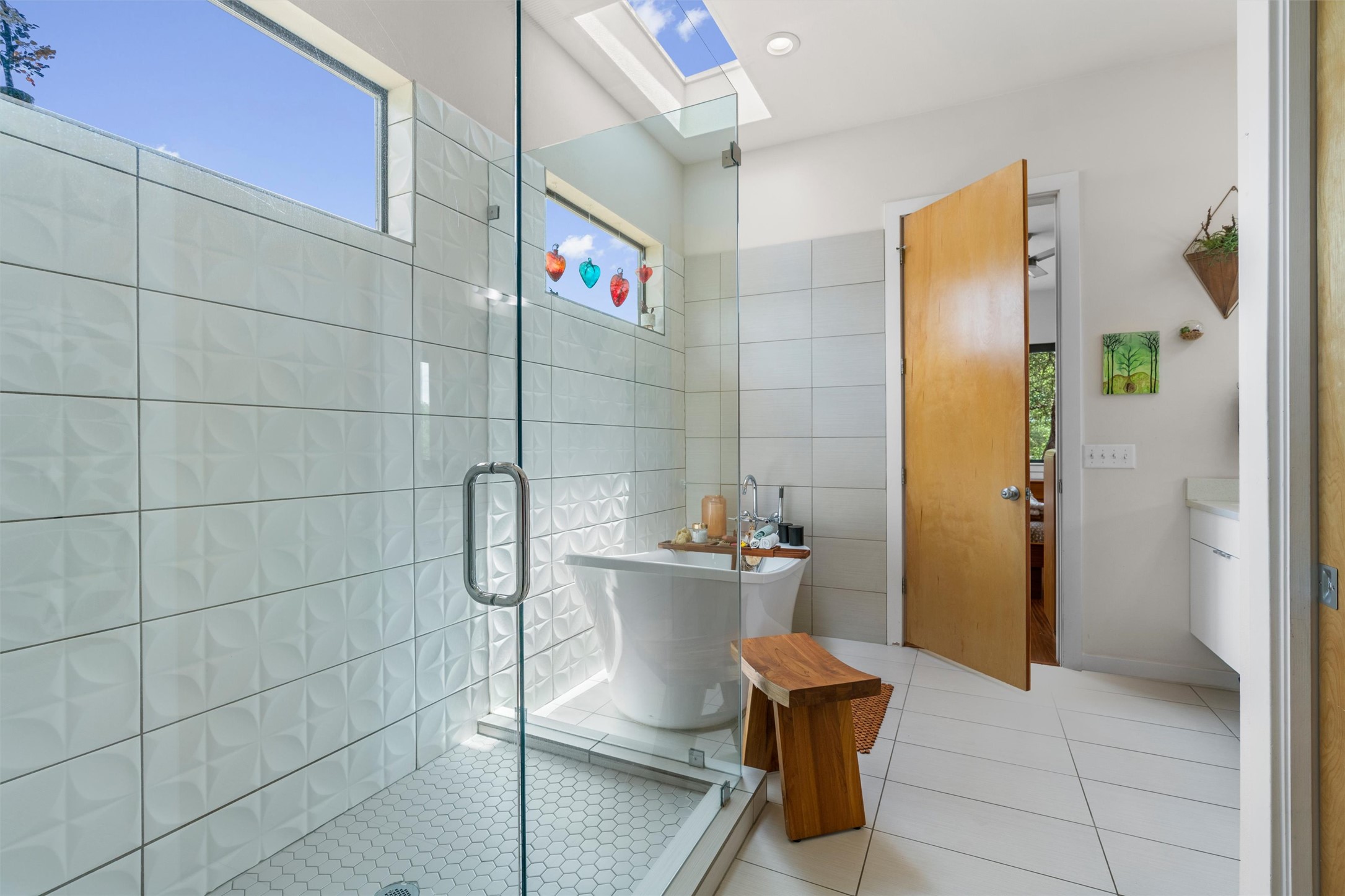 408 Starlight Village Loop Leander, TX 78641 - Photo 21 of 40 An airy bathroom features a freestanding tub and walk-in shower, bathed in natural light from a skylight.