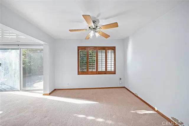 an empty room with windows and fan