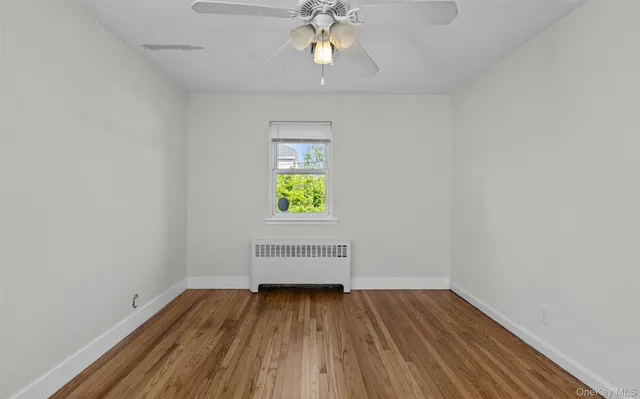 an empty room with a window and wooden floor