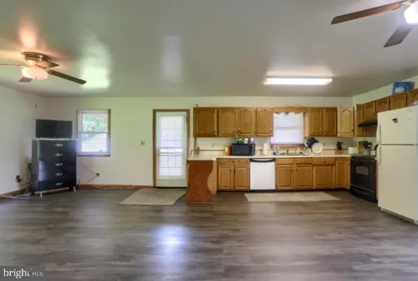 a view of a kitchen with furniture a ceiling fan and wooden floor