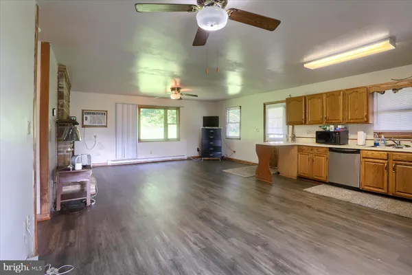 a view of an empty room with wooden floor fireplace and a window