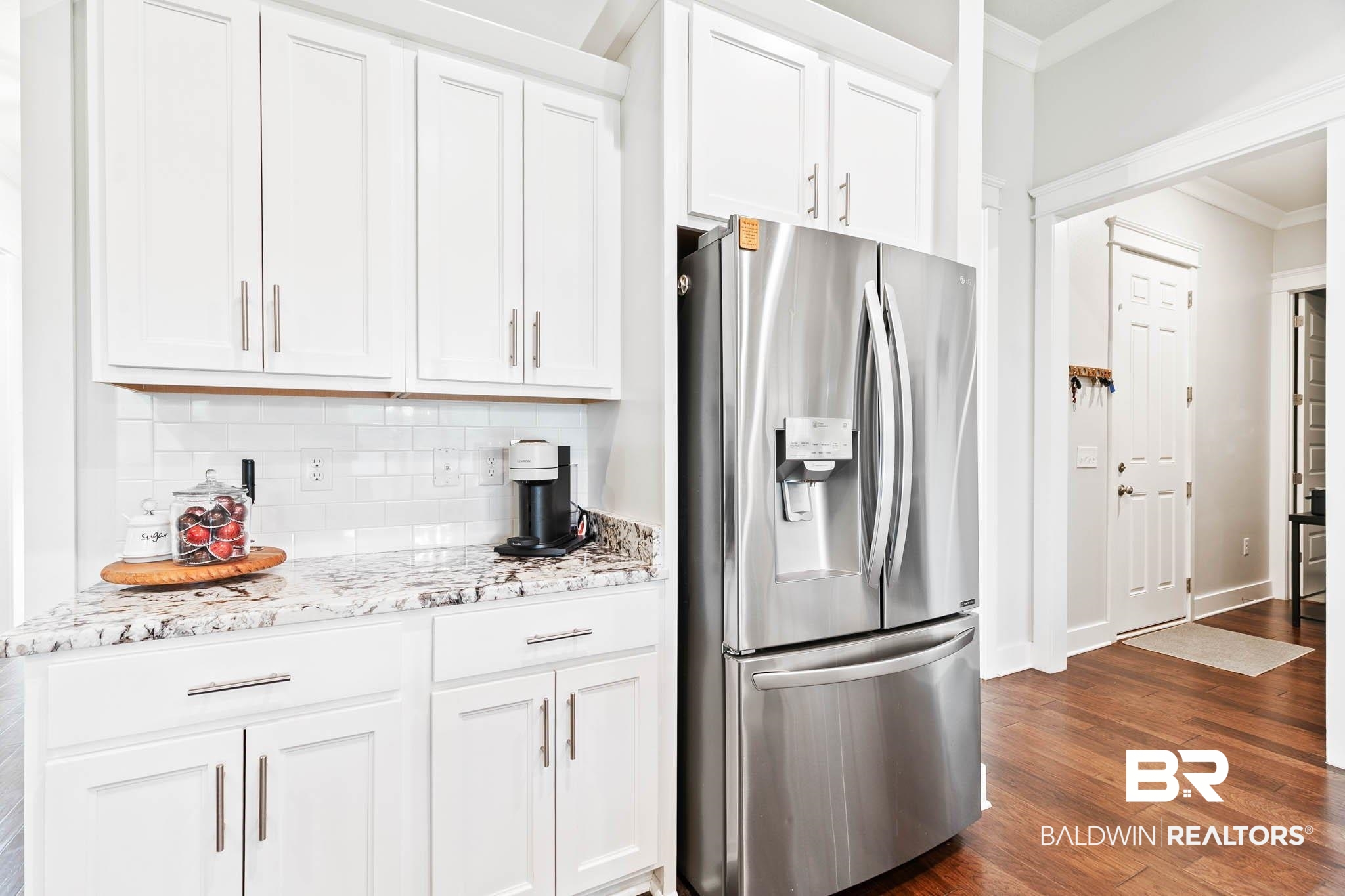12785 Warbler Street Daphne, AL 36527 - Photo 10 of 53 Kitchen featuring stainless steel fridge with ice dispenser, crown molding, decorative backsplash, dark wood finished floors, and light stone countertops