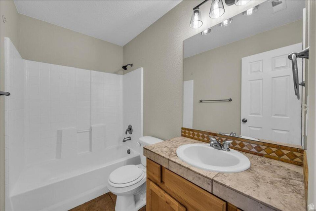 3155 South Hidden Dr Street, Unit 248 St. George, UT 84790 - Photo 14 of 24 Bathroom featuring a white tub/shower combination, a vanity with a tiled countertop, a built-in sink, and a wall-mounted mirror with overhead lighting
