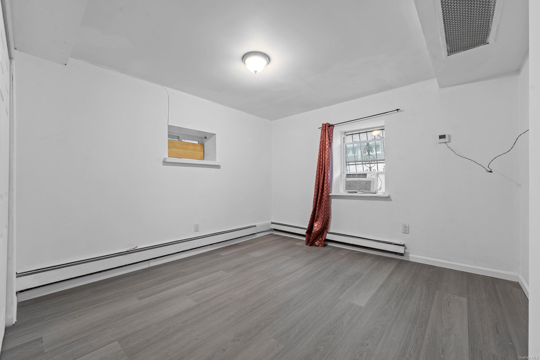 35-18 108th Street Queens, NY 11368 - Photo 4 of 20 Empty room featuring a baseboard heating unit, cooling unit, and hardwood / wood-style flooring