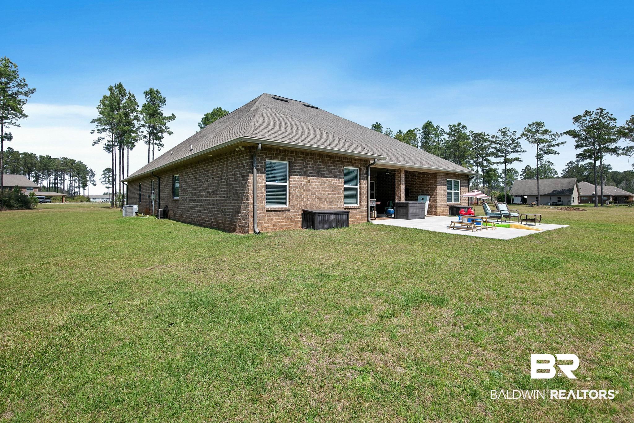 12750 B Jenkins Pit Road Daphne, AL 36527 - Photo 60 of 89 Back of property featuring a patio, a yard, brick siding, and roof with shingles