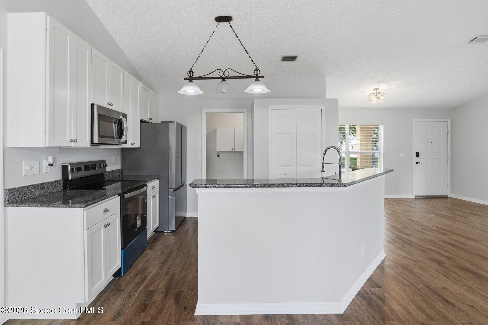 2005 Lansing Street Melbourne, FL 32935 - Photo 15 of 47 a kitchen with stainless steel appliances granite countertop a refrigerator a stove a sink a microwave and wooden floor