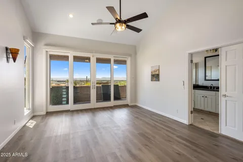 an empty room with wooden floor and a ceiling fan