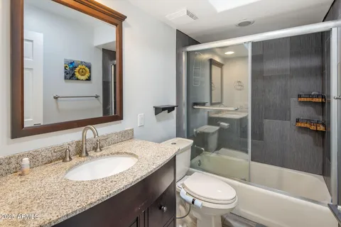 a bathroom with a granite countertop toilet sink and shower
