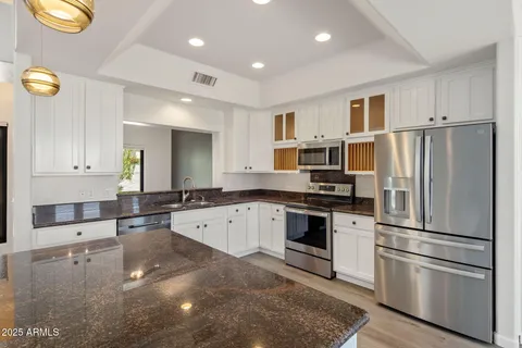 a large kitchen with stainless steel appliances granite countertop a refrigerator and a stove top oven
