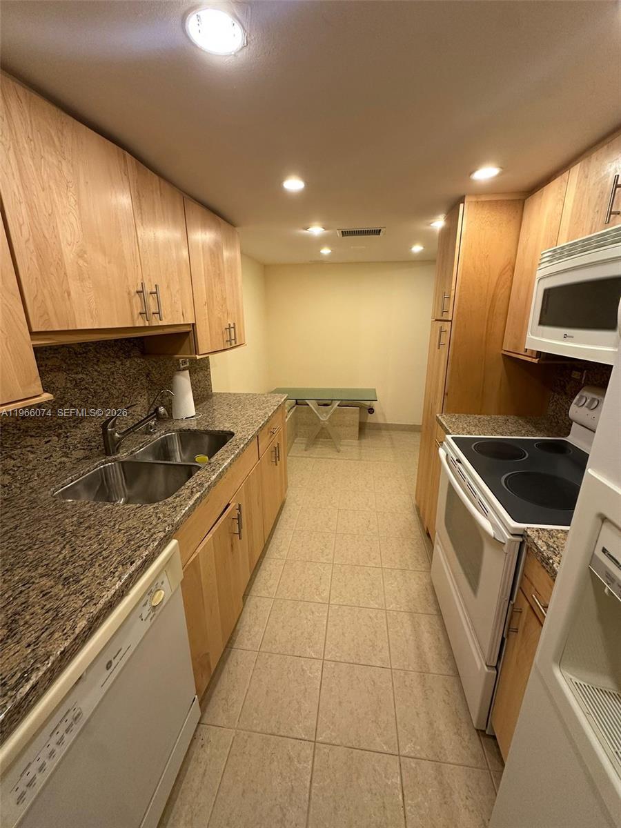 6039 Collins Avenue, Unit 1625 Miami Beach, FL 33140 - Photo 8 of 45 a large kitchen with stainless steel appliances a sink a stove and a microwave oven