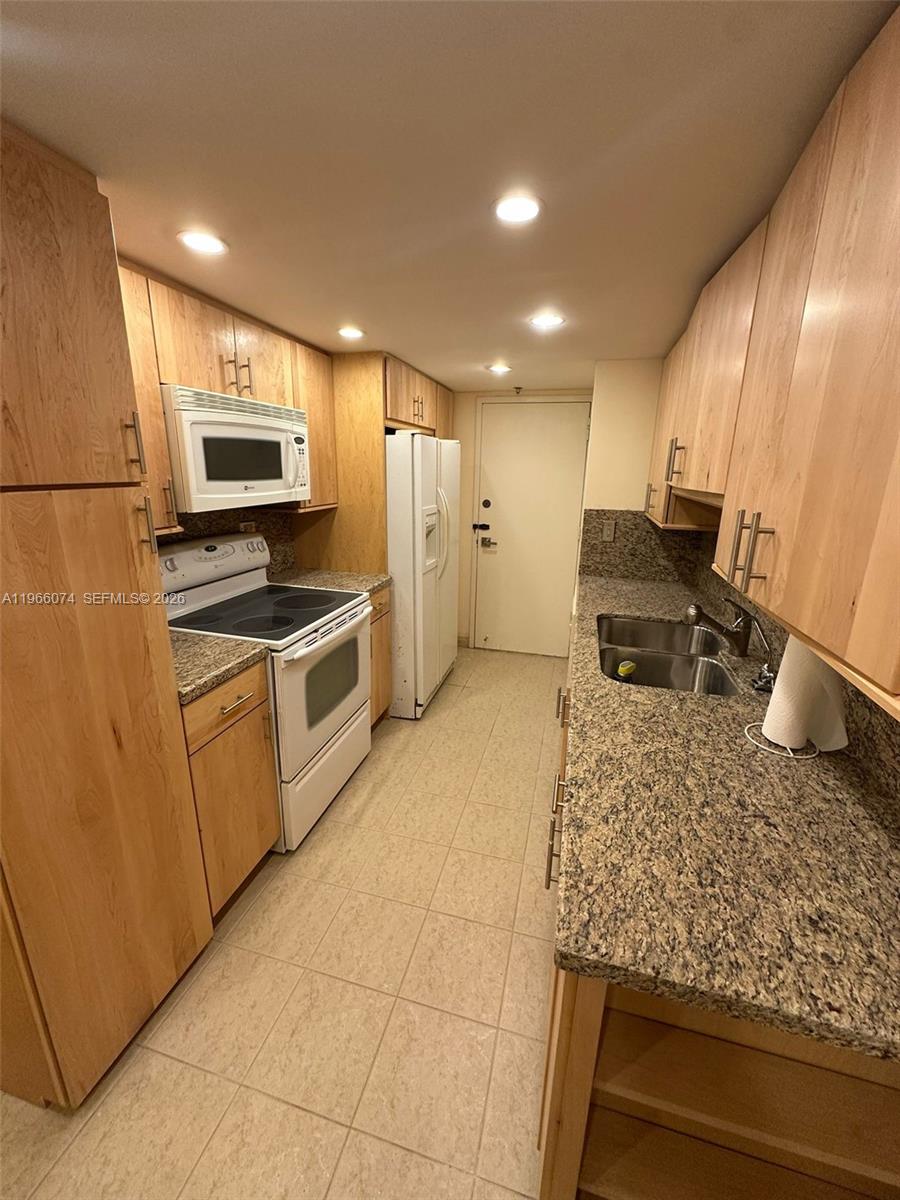 6039 Collins Avenue, Unit 1625 Miami Beach, FL 33140 - Photo 9 of 45 a kitchen with stainless steel appliances granite countertop a sink stove and refrigerator