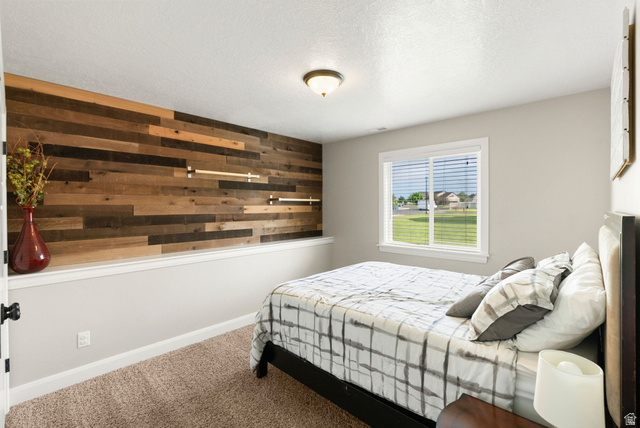 2485 South 1100th Street West Logan, UT 84321 - Photo 32 of 53 Bedroom featuring a plank-style accent wall, carpeted flooring, and a single window with blinds