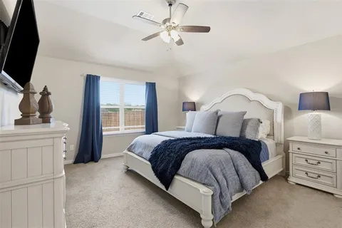 a spacious bedroom with a bed and a flat tv screen on dresser
