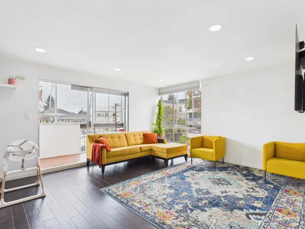 a living room with furniture kitchen view and a large window
