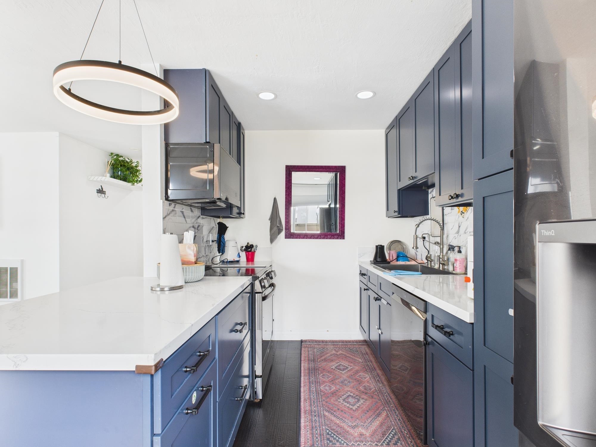 4099 Howe Street, Unit 202 Oakland, CA 94611 - Photo 8 of 19 Kitchen with blue cabinets, stainless steel appliances, recessed lighting, hanging light fixtures, and tasteful backsplash