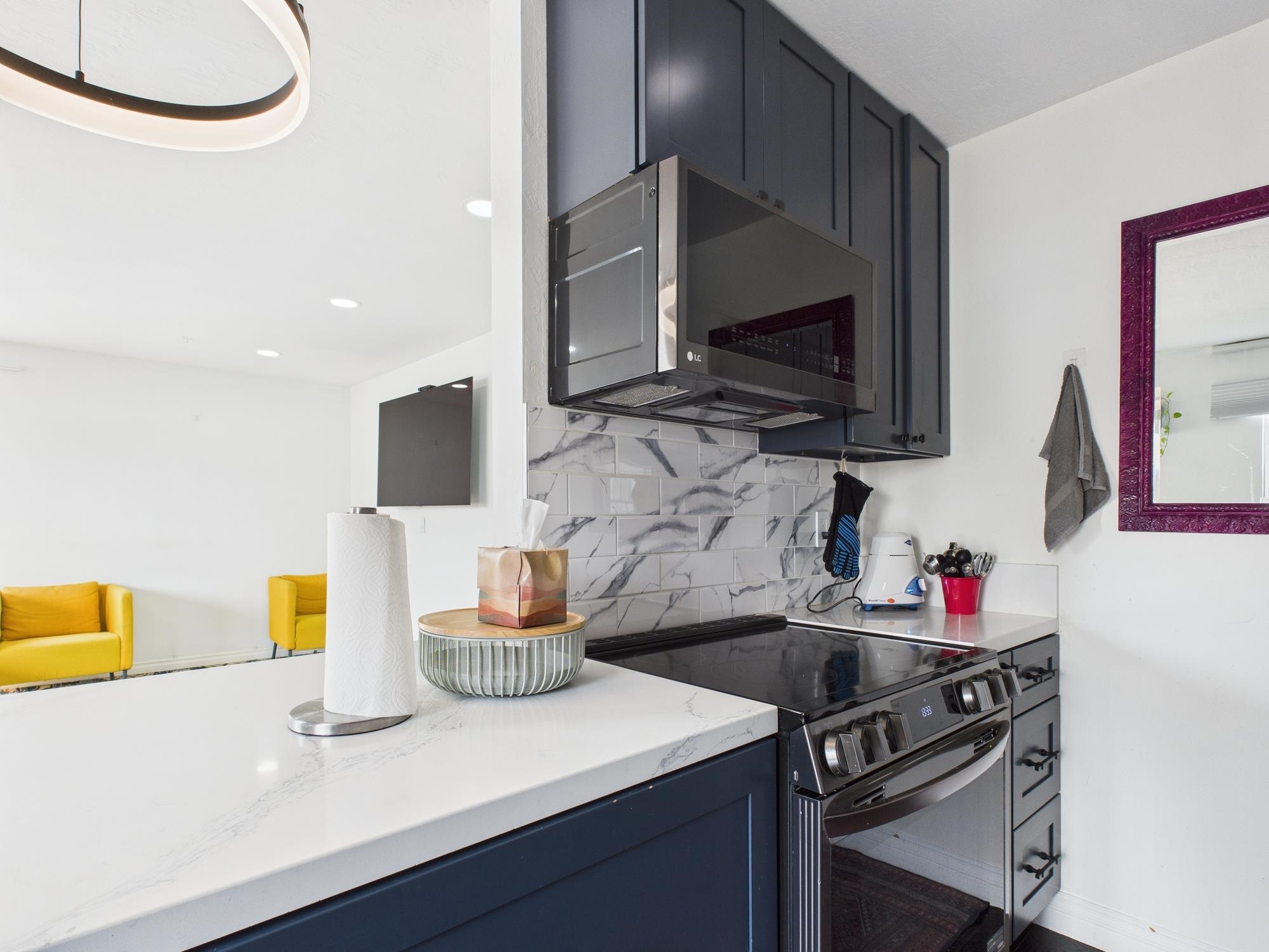 4099 Howe Street, Unit 202 Oakland, CA 94611 - Photo 10 of 19 Kitchen featuring black / electric stove, decorative backsplash, blue cabinetry, light stone counters, and stainless steel microwave