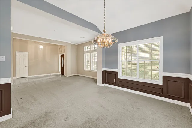 a view of an empty room with chandelier and a fireplace