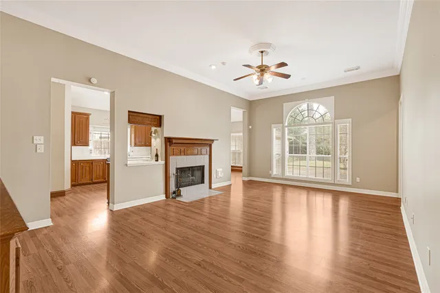 an empty room with wooden floor fireplace and windows