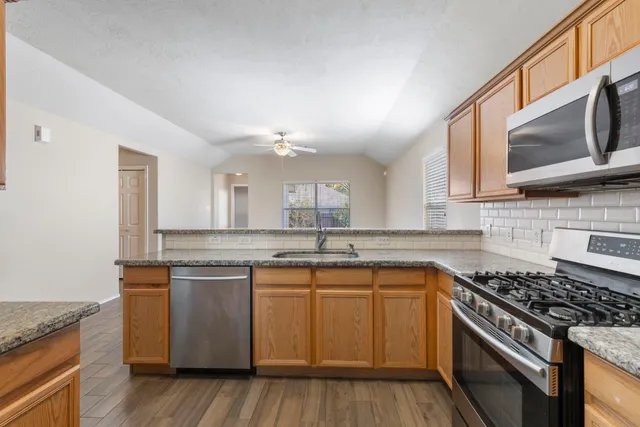 a kitchen with stainless steel appliances granite countertop a stove a sink and a microwave