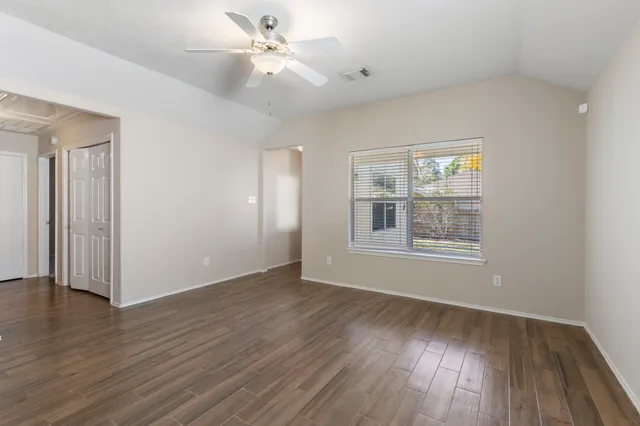 a view of an empty room with wooden floor and a window