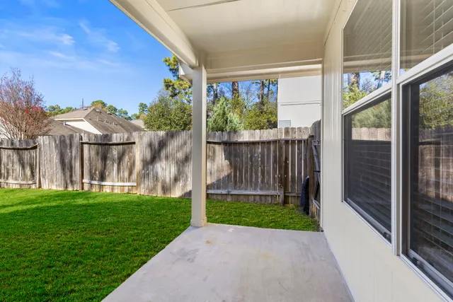 a view of a house with a small yard and a large tree with wooden fence