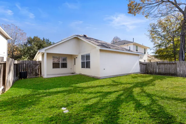 a yellow house with a small yard and wooden fence